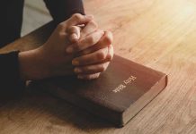 Hands praying on a Bible