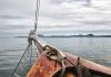 Sailboat bow facing calm sea and distant mountains