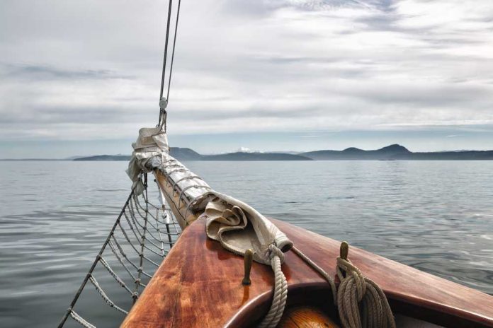 375934579 featured image Sailboat bow facing calm sea and distant mountains