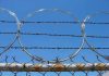 Barbed wire and metal fencing against blue sky