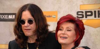 A celebrity couple posing together at a red carpet event smiling and dressed in stylish outfits