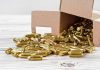 Box of brass bullets spilled on wooden surface