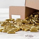 Box of brass bullets spilled on wooden surface