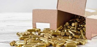 Box of brass bullets spilled on wooden surface