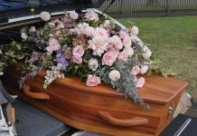 Coffin with flowers in the back of a hearse.