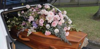 Coffin with flowers in the back of a hearse.