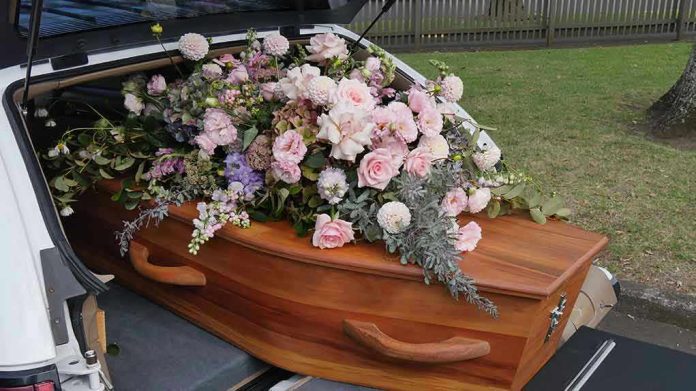 Coffin with flowers in the back of a hearse.