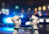Hands in handcuffs in front of police cars.