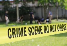Yellow crime scene tape blocking grassy area.