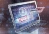 Person holding credit card near laptop displaying Fraud.