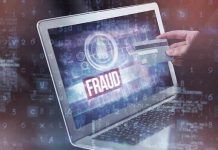 Person holding credit card near laptop displaying Fraud.
