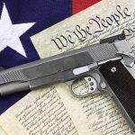 A handgun placed on top of the U.S. Constitution and an American flag
