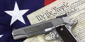 A handgun placed on top of the U.S. Constitution and an American flag