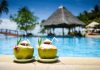 Two coconut drinks with straws beside a swimming pool