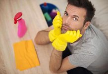 Man in yellow gloves looking frustrated while preparing to clean