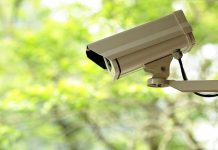 A security camera mounted outdoors with a blurred green background