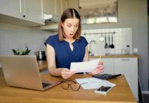 Woman shocked reading a document at home.