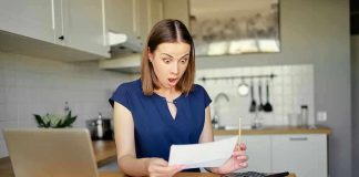 Woman shocked reading a document at home.