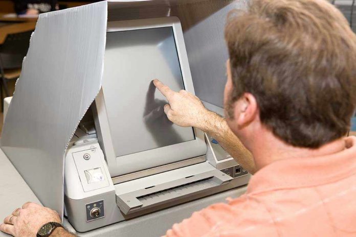 9389761 Person using touchscreen voting machine in polling booth.