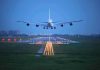 An airplane approaching the runway at night with landing lights illuminated