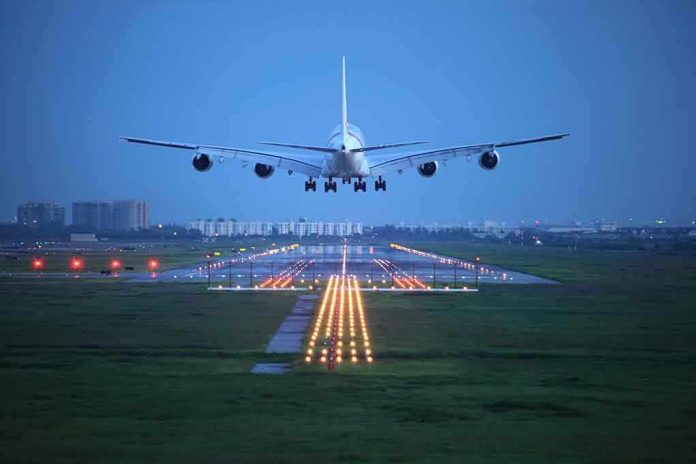 shutterstock_112881910.jpg An airplane approaching the runway at night with landing lights illuminated