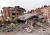 Rescue workers in orange uniforms on a collapsed building site after an earthquake